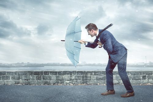 レジリエンス,Businessman with an umbrella is facing strong headwind